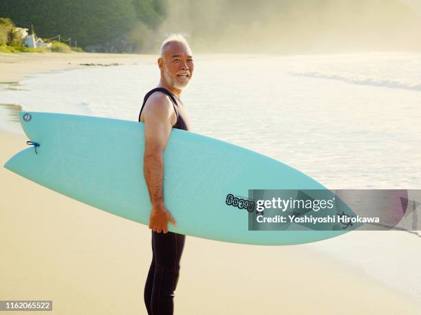 portrait of senior surfer with surfboard - surfer portrait fotografías e imágenes de stock