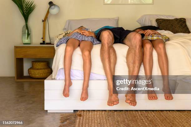 father sleeping with daughters on bed in hotel - three people bed stock pictures, royalty-free photos & images