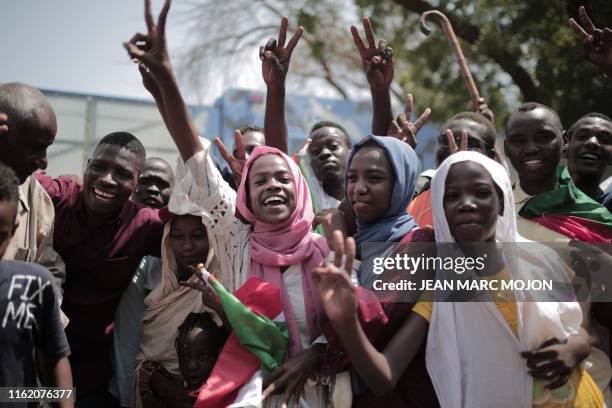 Sudanese men and women celebrate outside the Friendship Hall in the capital Khartoum where generals and protest leaders signed a historic...