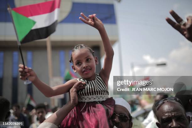 Young Sudanese girl waves a national flag as people celebrate outside the Friendship Hall in the capital Khartoum where generals and protest leaders...