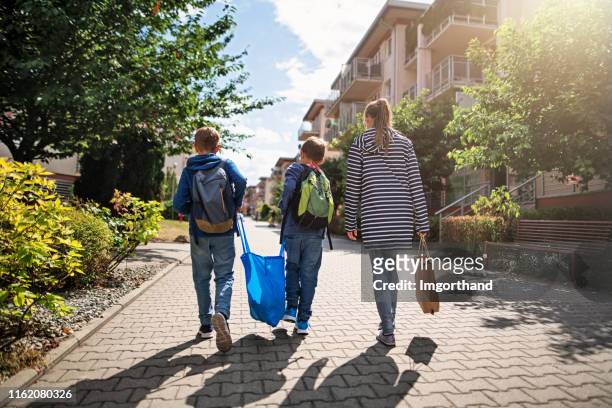 drie kinderen die een winkel huis meenemen in de resusable shopping bags - stadsdeel stockfoto's en -beelden