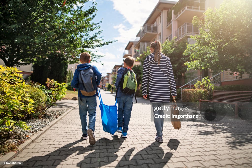 Three kids carrying shopping home in resusable shopping bags