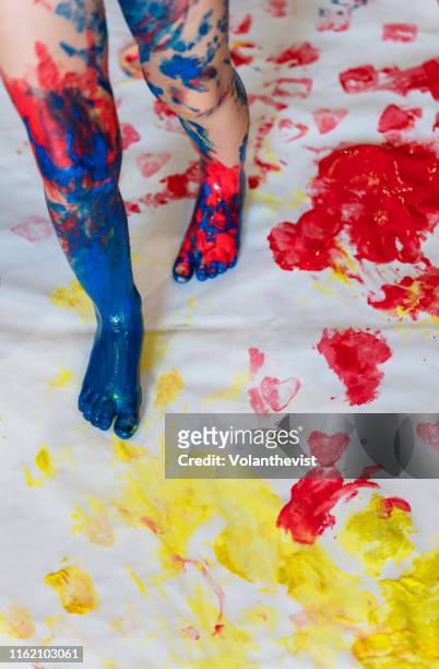 toddler girl playing and painting with feet on a paper - baby paint stock-fotos und bilder