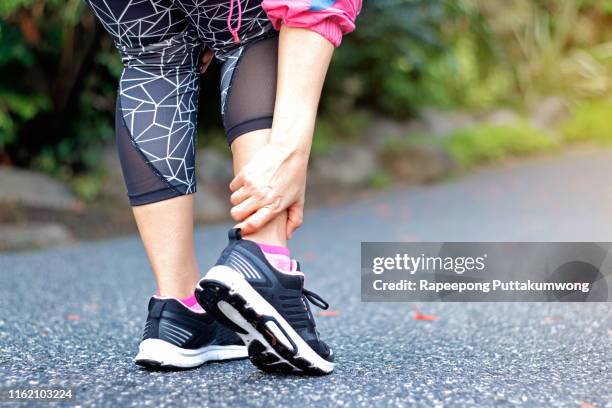 running sport injury. athletic woman runner touching foot in pain due to sprained ankle - sprain stock pictures, royalty-free photos & images
