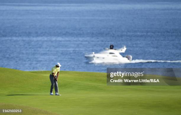 Tiger Woods of the United States putts on the 5th green as a yacht passes by during a practice round prior to the 148th Open Championship held on the...