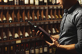 Close up portrait of sommelier holding wine bottle on wine cellar background.