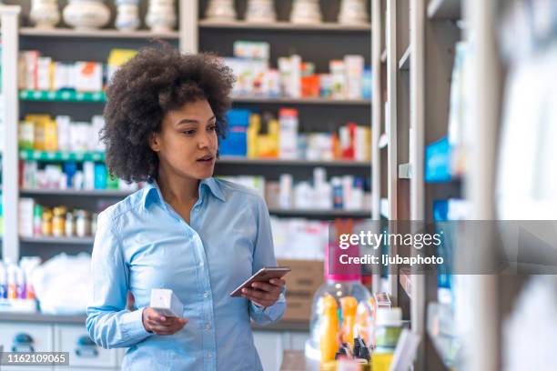 woman buying cosmetic in pharmacy store. woman uses smart phone while in pharmacy - make up looks stock pictures, royalty-free photos & images
