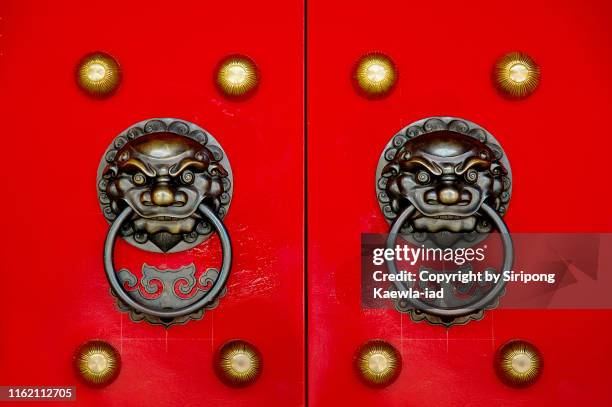 close up of the chinese style lion knocker on the red wooden gate. - door knocker stock pictures, royalty-free photos & images