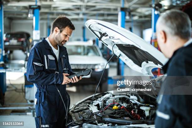 automonteur werken met auto diagnostic tool in een reparatiewerkplaats. - monteur stockfoto's en -beelden