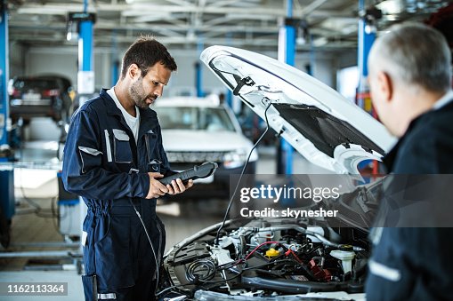 Auto mechanic working with car diagnostic tool in a repair shop. Auto mechanic working with car diagnostic tool in a repair shop.