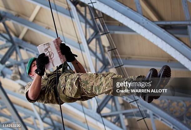 Royal Marine commando poses for pictures with the new James Bond book entitled 'Carte Blanche' as he abseils down from the station roof at a...