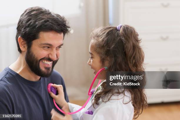 hispanic girl playing doctor with father - vestita da dottoressa foto e immagini stock