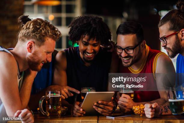 male friends watching game on tablet - crowd cheering bar stock pictures, royalty-free photos & images