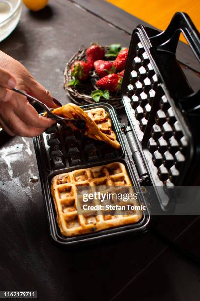 männlicher koch macht waffeln auf einer waffelmaschine - waffeln stock-fotos und bilder