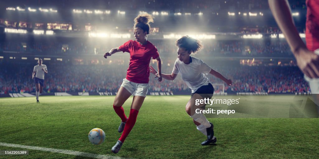 Women Soccer Players In Mid-Action During Game in Floodlit Stadium