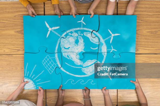 elementary students portraying a bright future of renewable energy - puzzle 4 puzzle pieces stock pictures, royalty-free photos & images