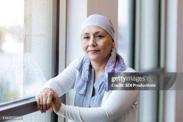 mid adult woman fighting cancer poses for camera - fighting cancer stock pictures, royalty-free photos & images