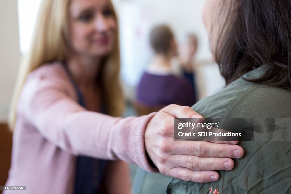 Close up photo of woman's hand comforting an unrecognizable woman