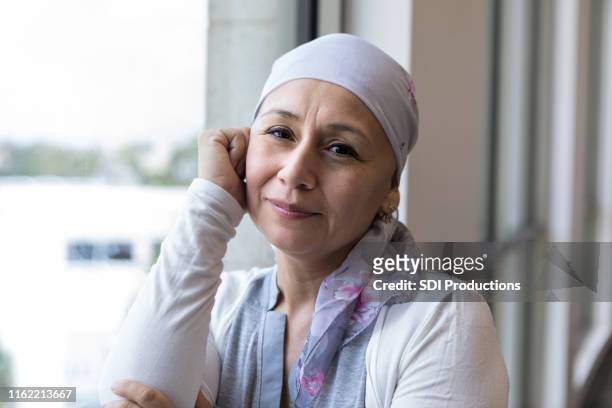 kankerpatiënt het dragen van een sjaal te bedekken hoofd ziet er vredig - cancer survivor stockfoto's en -beelden