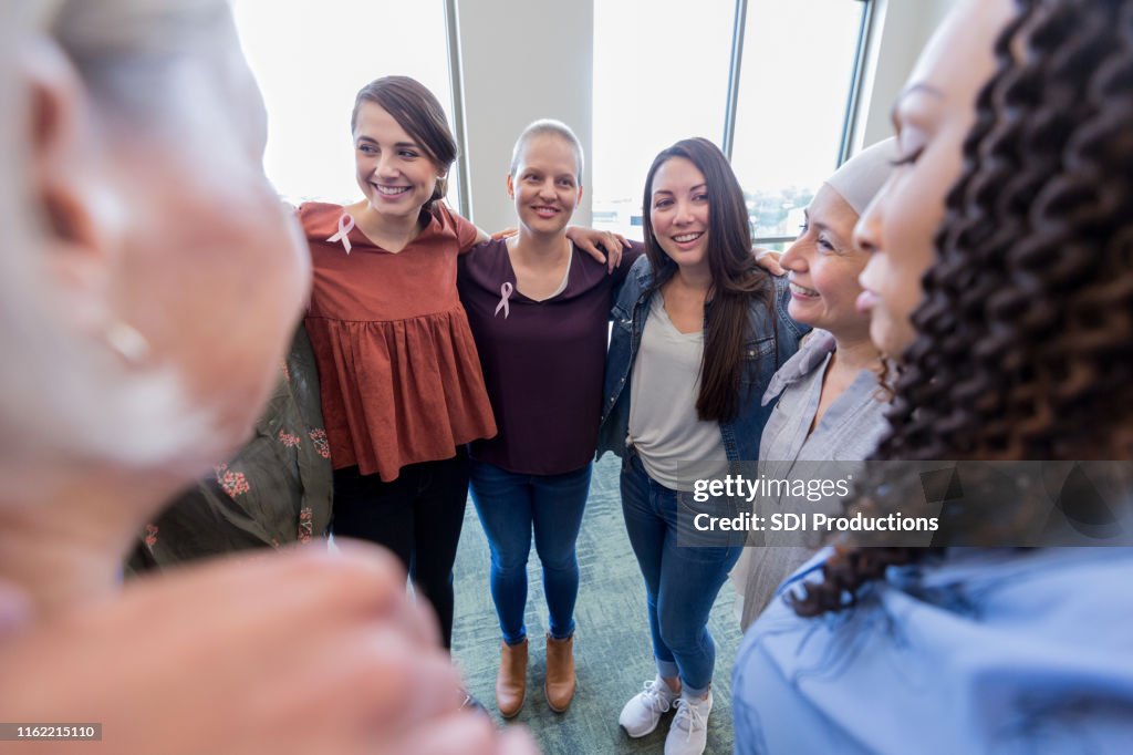 Cancer patients stand in circle with arms on neighbor's shoulders