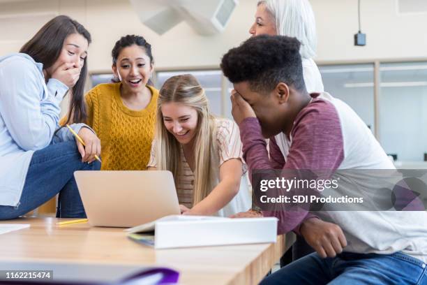 un adolescent embarrassé cache le visage pendant que ses amis regardent sa vidéo - taquiner photos et images de collection