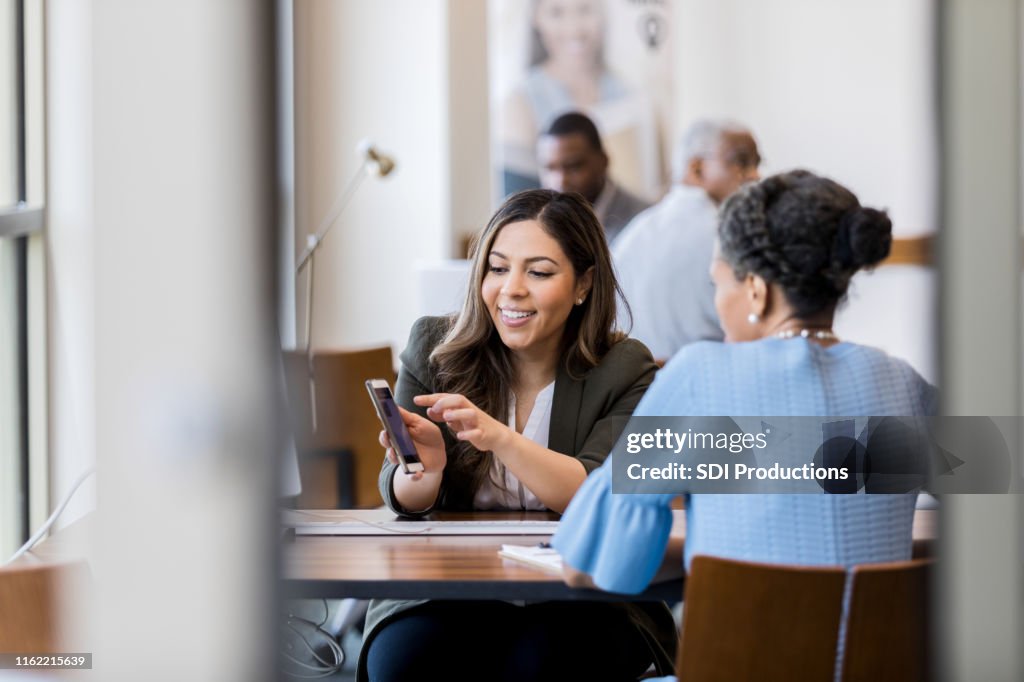 Cheerful bank employee shows customer banking app