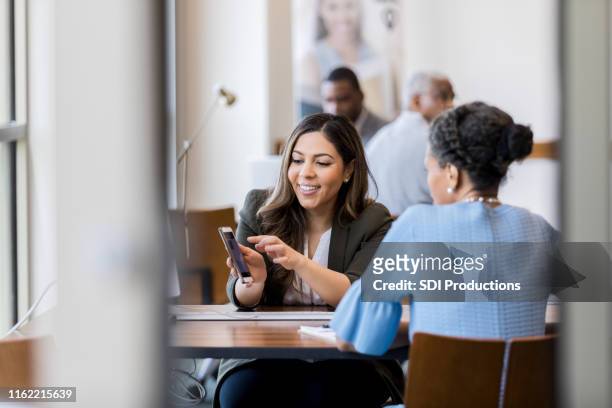 cheerful bank employee shows customer banking app - happy customer stock pictures, royalty-free photos & images