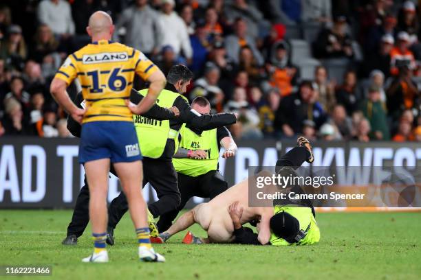 Streaker is apprehended during the round 17 NRL match between the Wests Tigers and the Parramatta Eels at Bankwest Stadium on July 14, 2019 in...