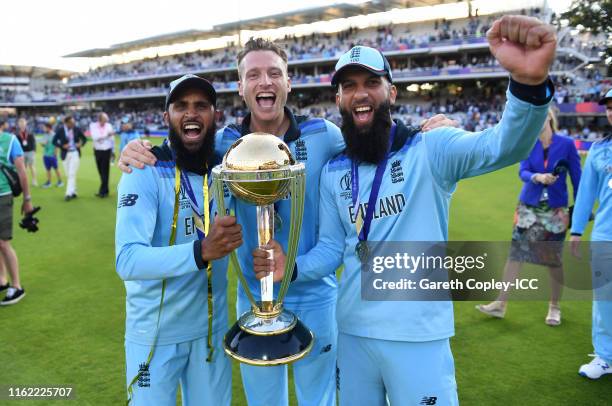 Moeen Ali, Jos Buttler and Adil Rashid celebrate with the trophy after winning the Final of the ICC Cricket World Cup 2019 between New Zealand and...