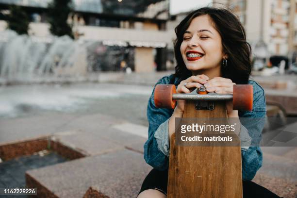 beautiful urban young female in the city with her longboard. - adult braces stock pictures, royalty-free photos & images
