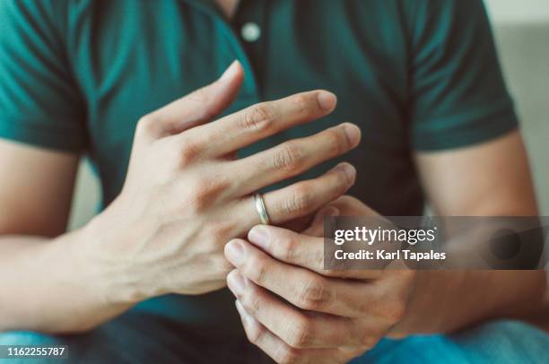 a young man wearing a green shirt is holding his wedding ring - men rings foto e immagini stock