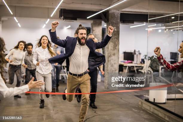 cheerful male freelancer celebrating the victory in sports race at casual office. - finishing line stock pictures, royalty-free photos & images