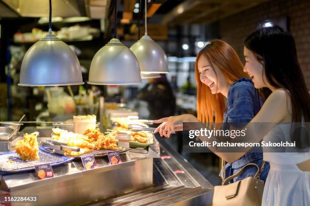 woman friends choosing food in buffet restaurant - buffet stock pictures, royalty-free photos & images