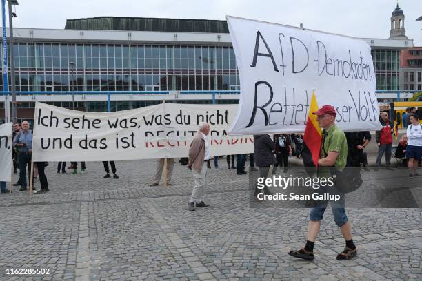 Supporter of the anti-Muslim Pegida movement holding a banner that reads: "AfD Democrats, Save Our People!", walks past leftist protesters prior to...