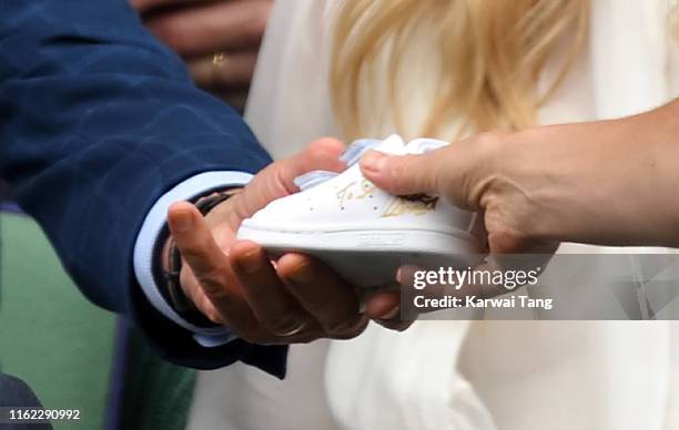 Stan Smith gives Catherine, Duchess of Cambridge a signed baby 'Stan Smith' trainer in the Royal Box during Men's Finals Day of the Wimbledon Tennis...