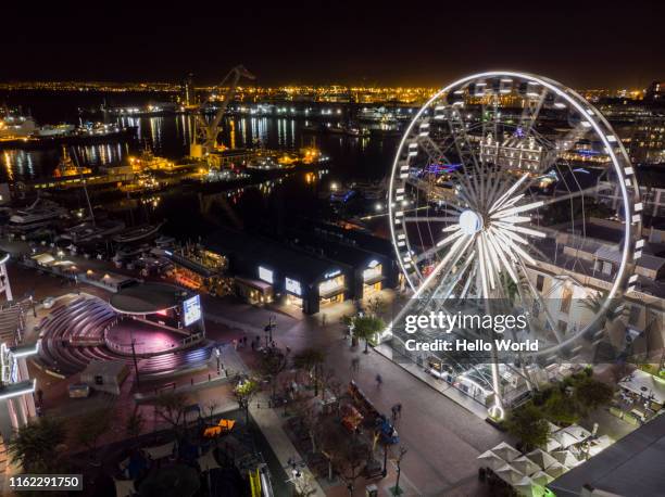 aerial shot of a lit ferris wheel and city lights at night - waterfront stock photos et images de collection