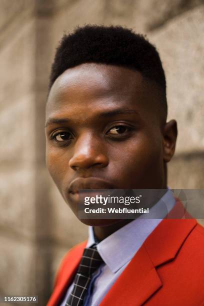 Portrait of young black man in a red suit standing outdoors