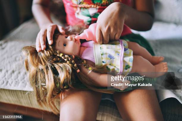 gir feeding her toy baby doll - baby doll stockfoto's en -beelden