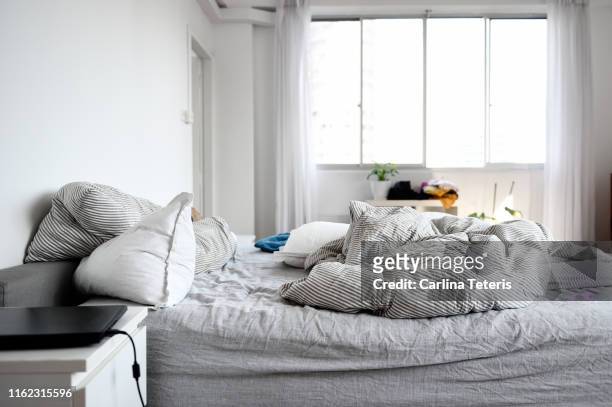messy bed in an apartment bedroom - messy bedroom stock-fotos und bilder