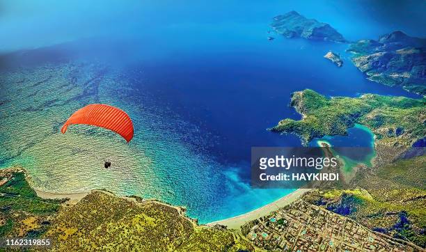在土耳其奧盧德尼茲的藍色瀉湖上空,滑翔傘在費蒂耶飛行 - aegean sea 個照片及圖片檔