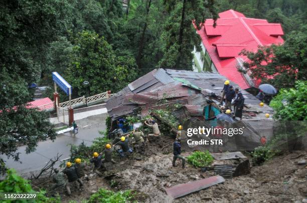 Rescuers work on a site after a building collapsed following heavy monsoon rainfall in the northern hill town of Shimla on 18 August 2019. - Two...