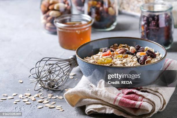 Variety of dried fruits. Nuts. Honey and oat flakes in bowl and different glass jars for cooking homemade healthy breakfast muesli or granola energy...