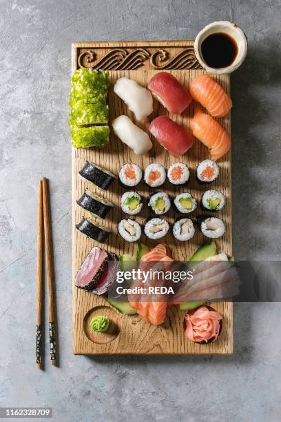 Sushi Set nigiri sashimi and sushi rolls on wooden serving board with soy sauce and chopsticks over grey concrete background. Flat lay. Space. Japan...