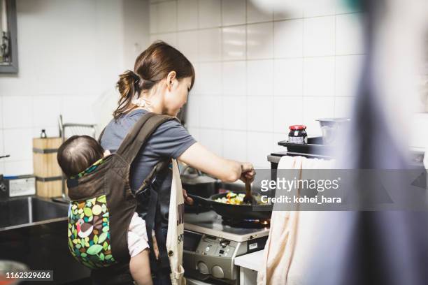 woman with baby cooking in the kitchen - asian mother cooking imagens e fotografias de stock