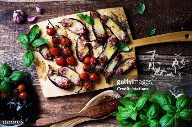 baked eggplant stuffed with mozzarella cheese and tomatoes, messy table - aubergine stock pictures, royalty-free photos & images