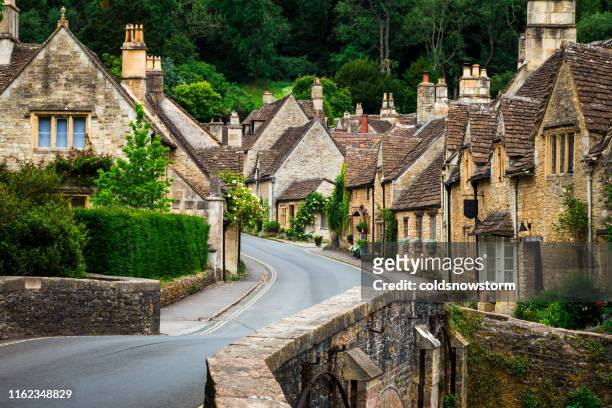 traditional idyllic english countryside village with cosy cottages and narrow road - english culture stock pictures, royalty-free photos & images