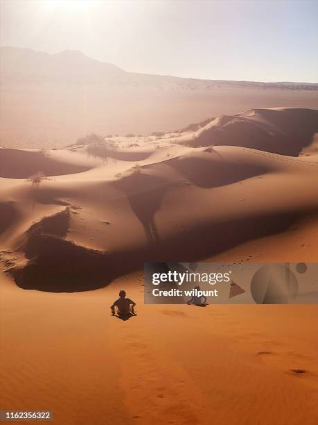 red sand dune sand boarding fun sliding down - sand boarding stock pictures, royalty-free photos & images