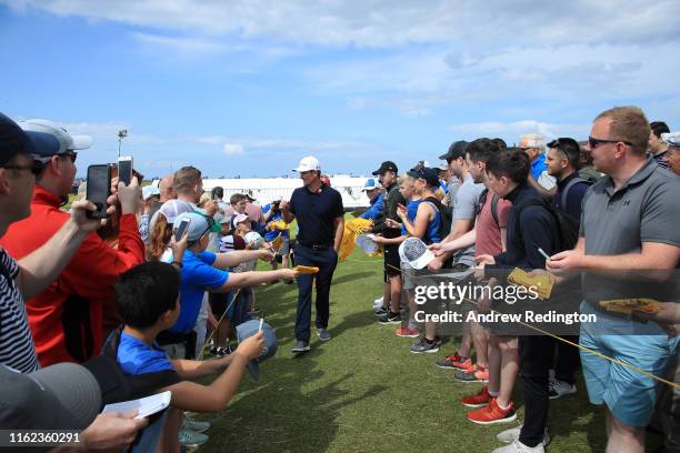 Justin Rose of England signs autographs for the crowds during a practice round prior to the 148th Open Championship held on the Dunluce Links at...