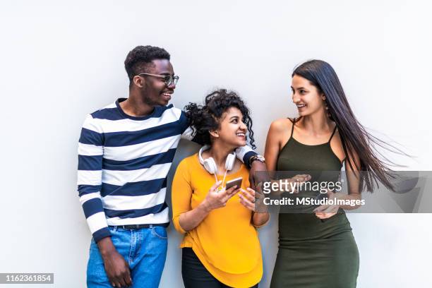 groep van lachende millennials met behulp van mobiele telefoon - 3 teenagers mobile outdoors stockfoto's en -beelden