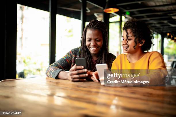 two millenial friends using mobile phone. - sending payment stock pictures, royalty-free photos & images